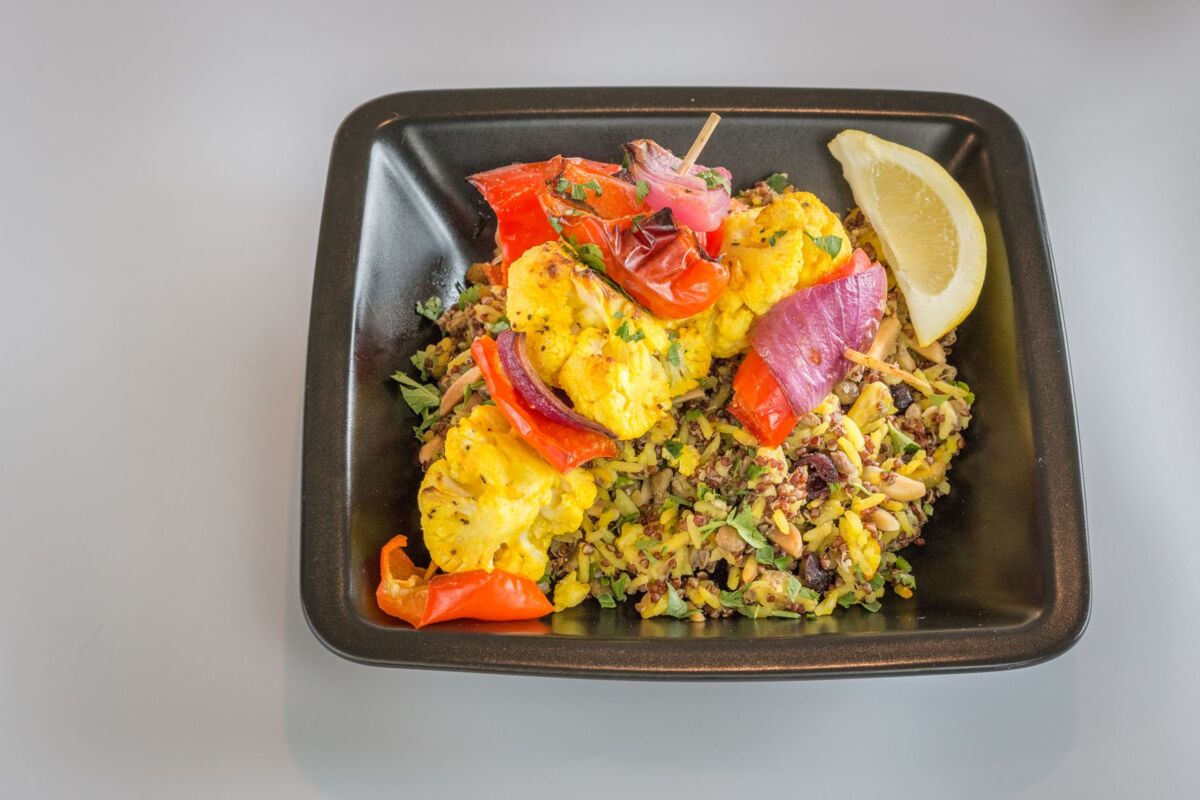 Delicious grilled vegetable skewer over mixed rice, garnished with a lemon wedge.