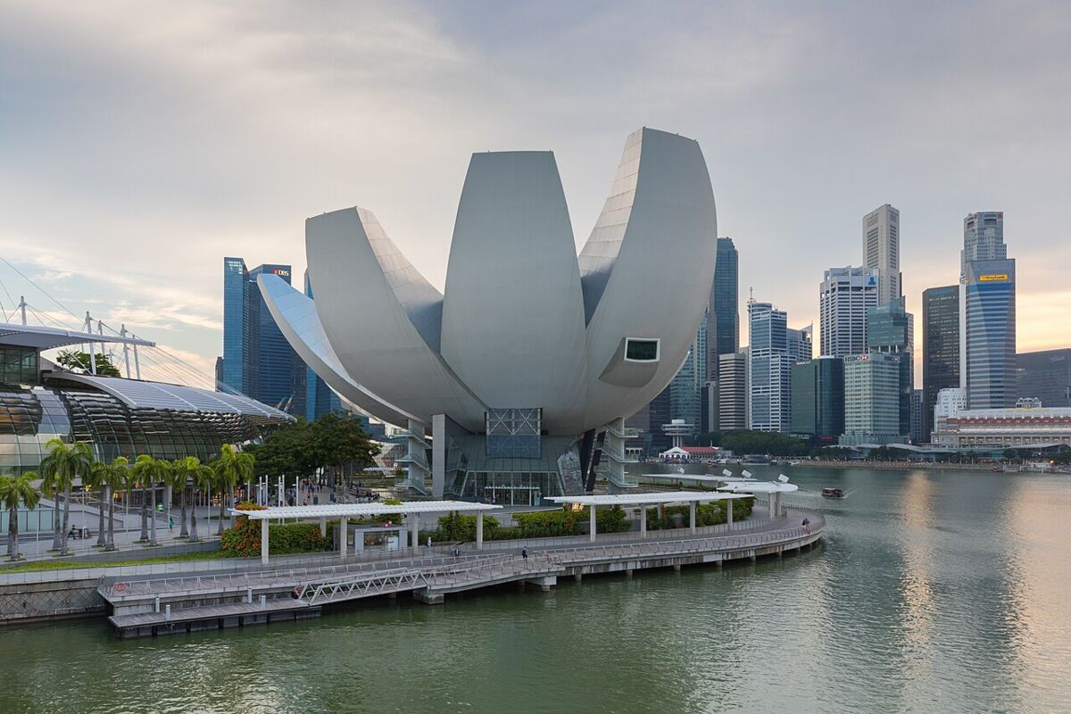 The lotus-shaped ArtScience Museum beside Marina Bay with the Singapore city skyline behind it at dusk