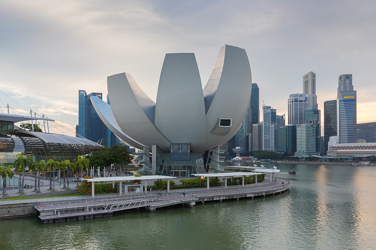 The lotus-shaped ArtScience Museum beside Marina Bay with the Singapore city skyline behind it at dusk