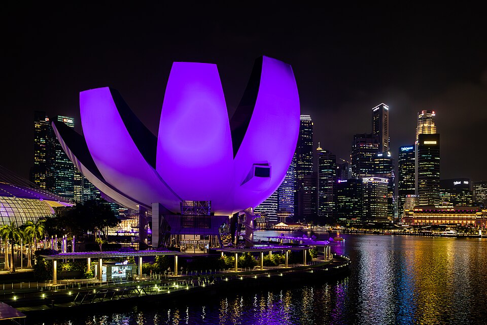 The ArtScience Museum illuminated in bright purple light at night against the Singapore skyline