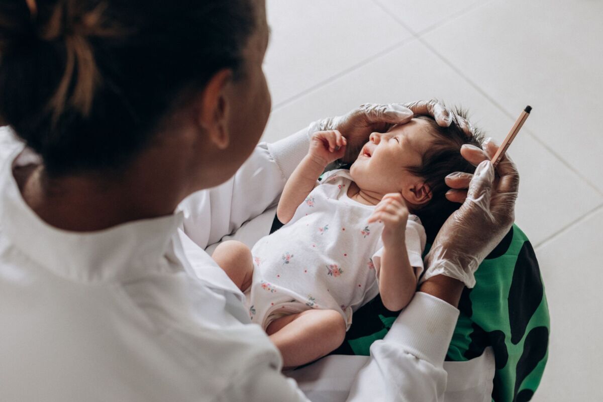 A medical professional examines a newborn baby indoors, highlighting healthcare and care.