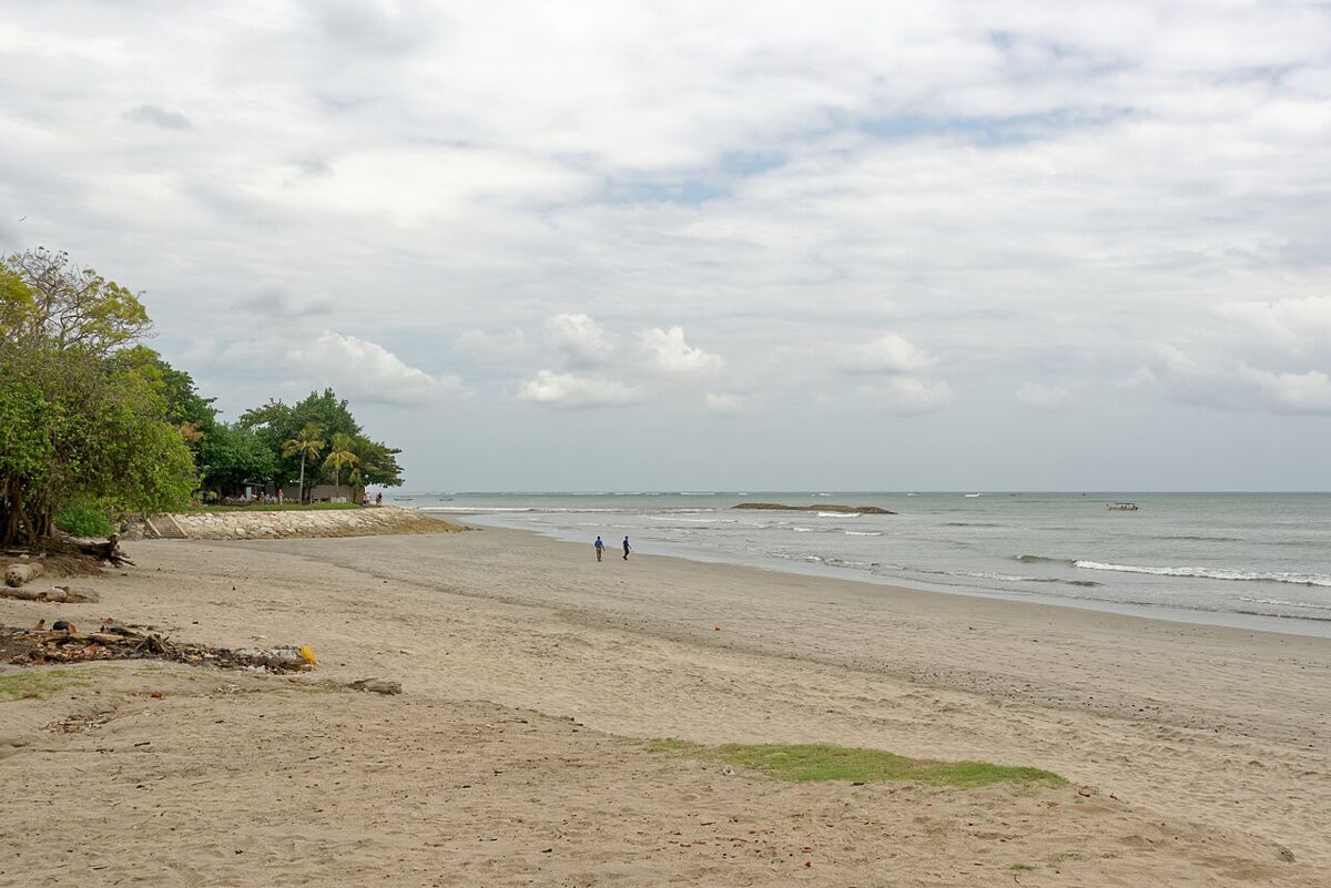 Wide sandy beach with gentle surf and palm trees at Jerman Beach, Kuta, Bali