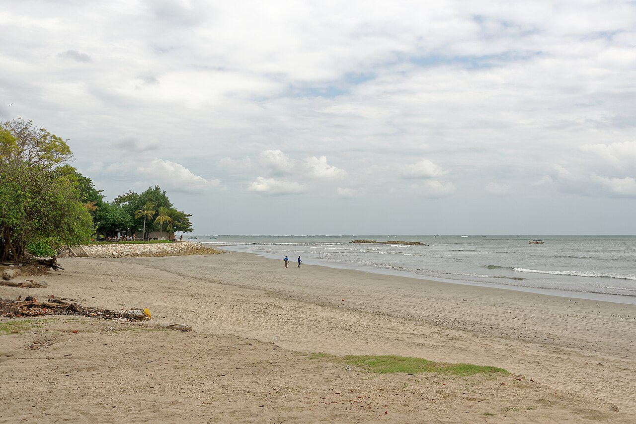 Wide sandy beach with gentle surf and palm trees at Jerman Beach, Kuta, Bali