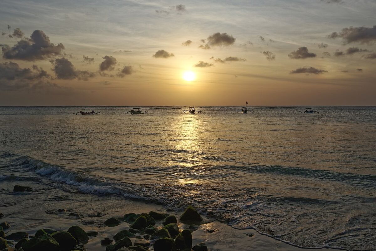 Golden sunset over the sea with outrigger boats off Kuta beach, Bali