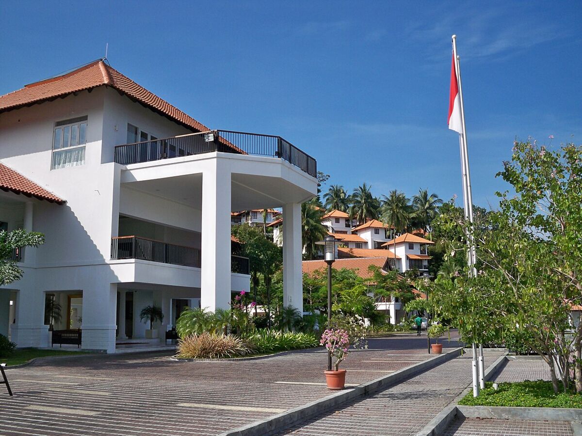 White resort building with Indonesian flag and palm-covered villas at Nongsa Point Marina Resort, Batam