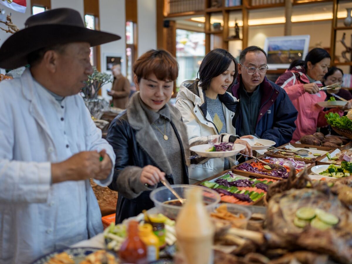 A diverse group of adults serving themselves at a buffet featuring a variety of fresh foods.