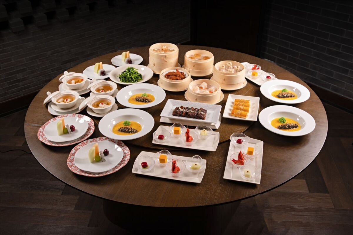 Diverse Asian dishes including dim sum and soups beautifully arranged on a large round table.