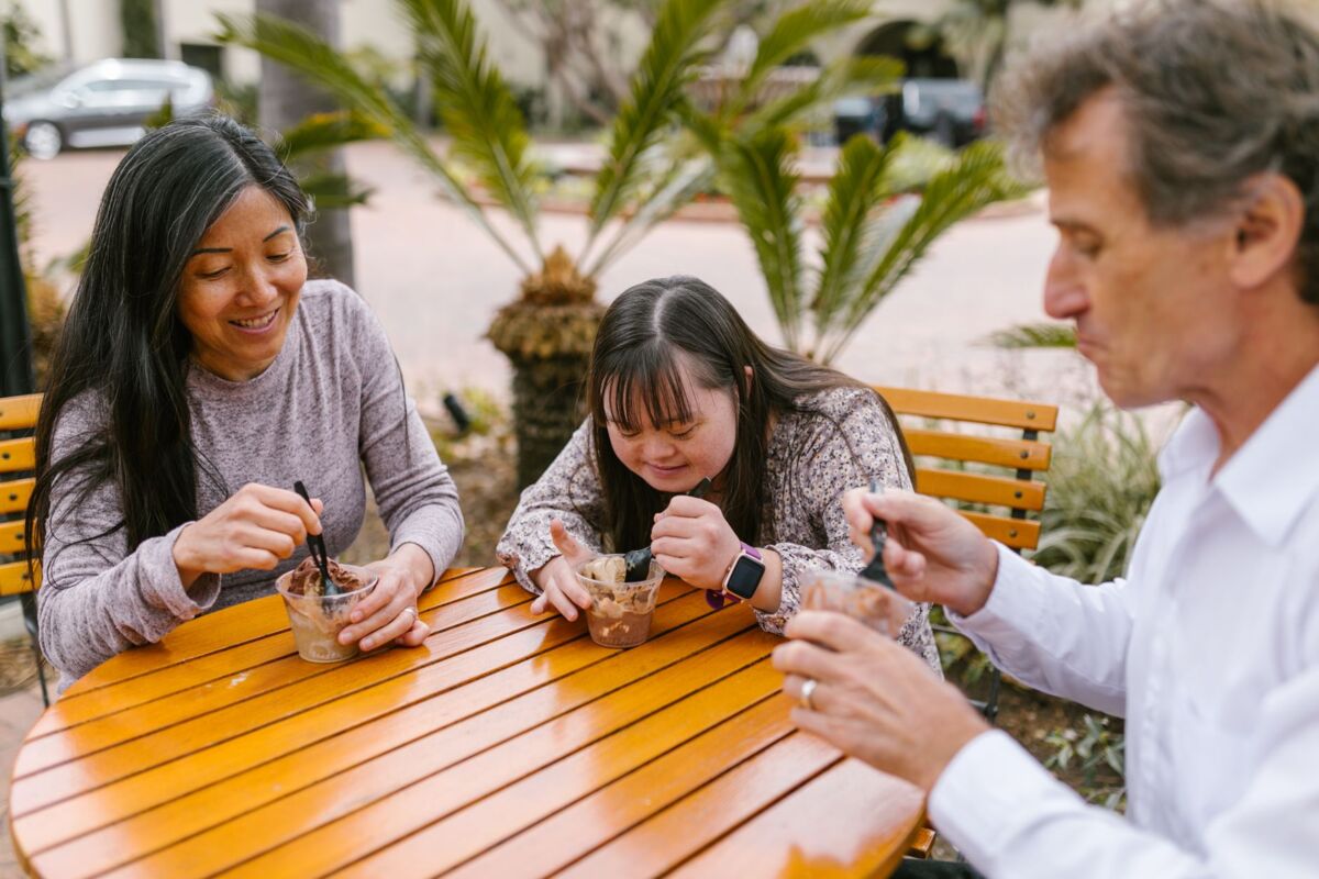 A happy family shares quality time enjoying ice cream outdoors on a sunny day.
