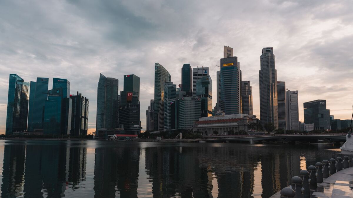 Dramatic skyline of Singapore reflecting on waterfront at dusk with towering skyscrapers.