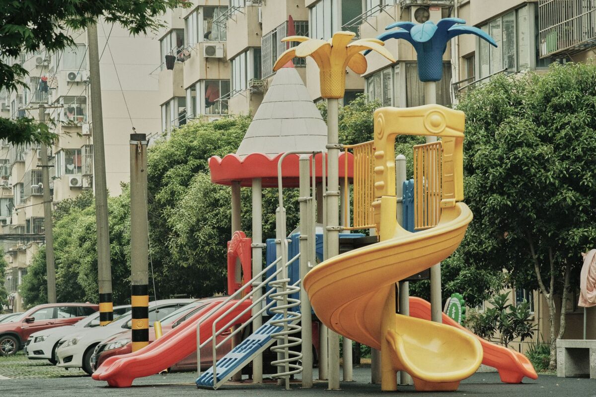 Vibrant playground with slides and equipment in an urban park setting surrounded by apartment buildings.