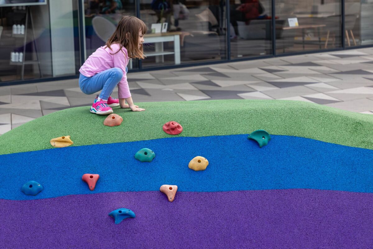 Young girl enjoying climbing a vibrant playground structure.