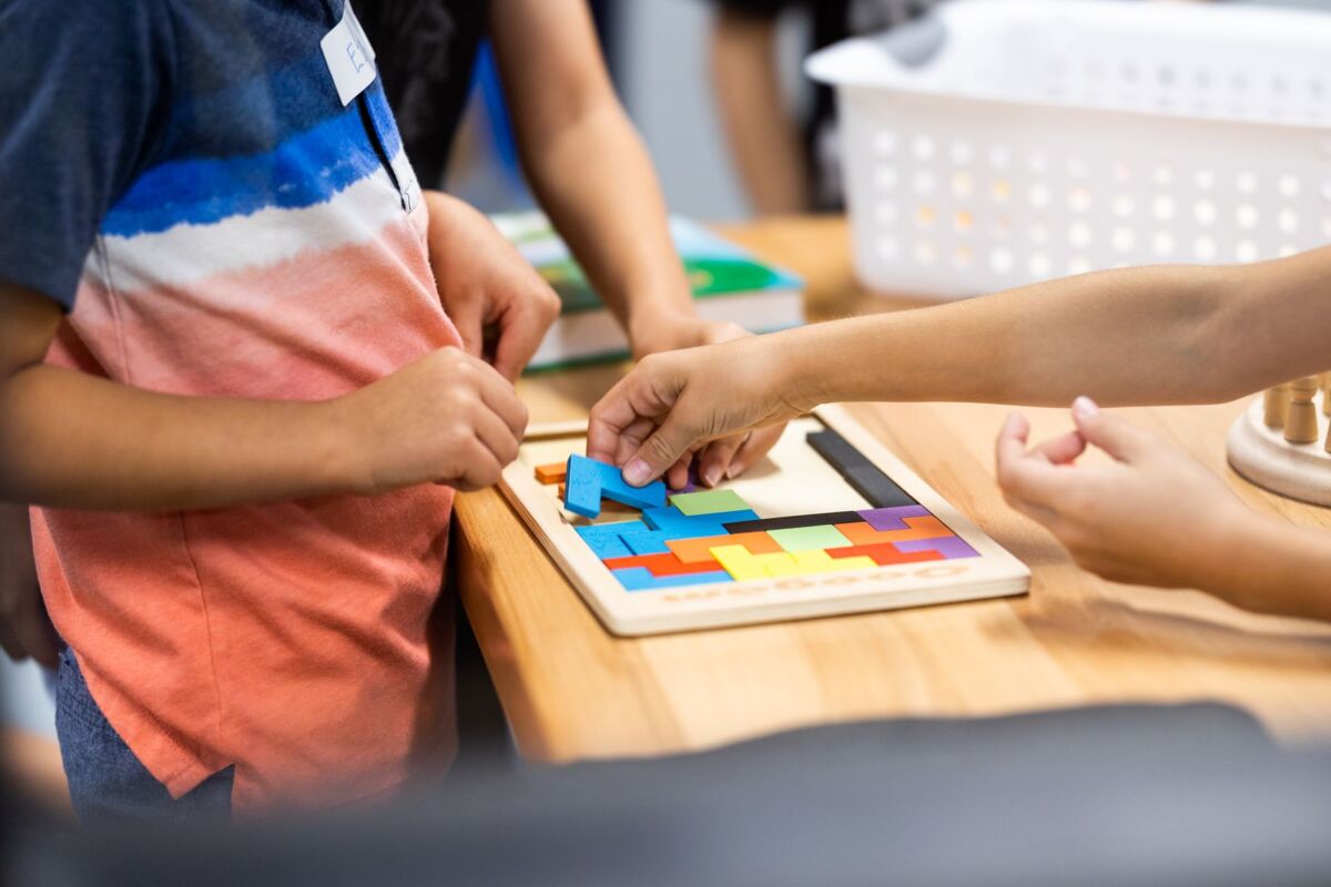 Young children learning with colorful puzzle pieces in a classroom setting.