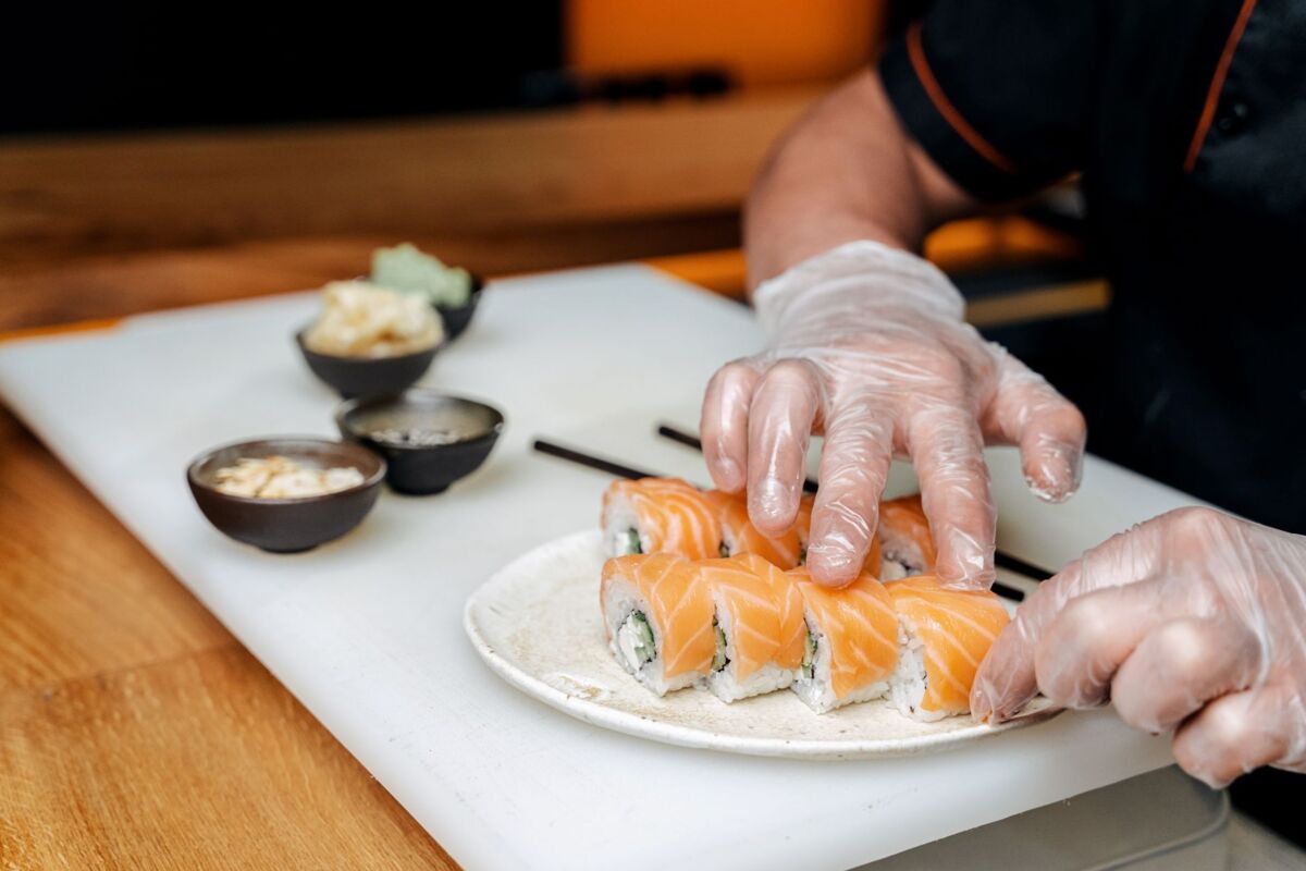 Close-up of a chef preparing fresh salmon sushi rolls with precision, showcasing sushi-making skills.