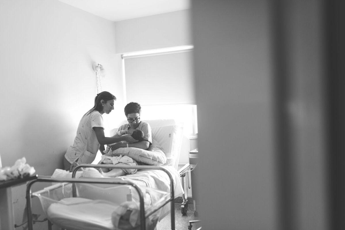 A nurse assisting a mother with her newborn in a hospital room.