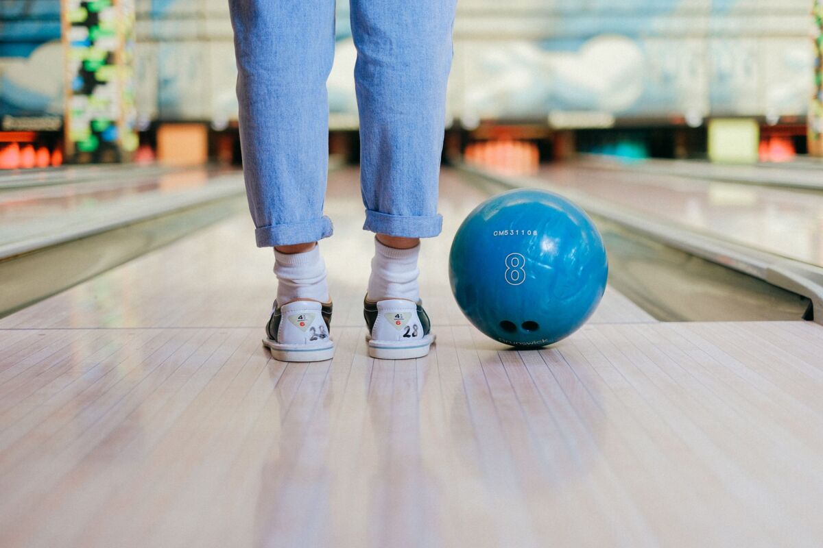 Child stands at bowling lane with bowling ball ready to play.