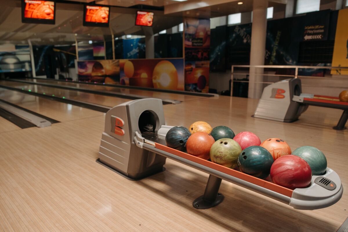 Vibrant bowling balls neatly arranged on a ball return system in an empty bowling alley.