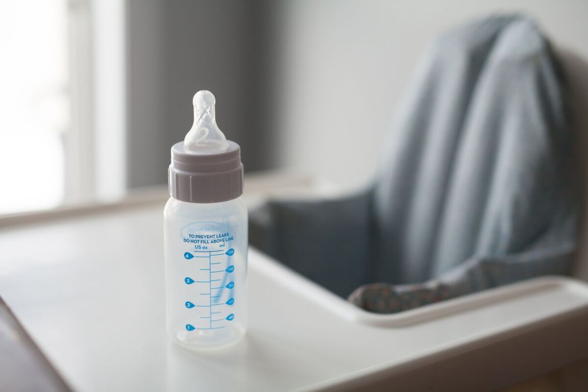 A baby bottle placed on a high chair, captured in natural light, suggesting a nurturing environment.
