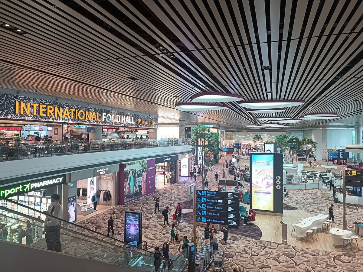 Terminal 4 departure hall interior at Changi Airport showing the International Food Hall, shops and travellers below a striped ceiling