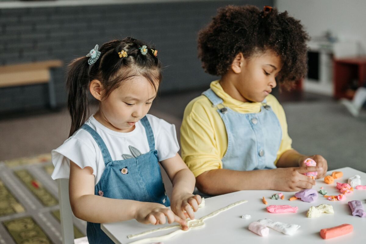 Two children playing with colorful clay indoors, fostering creativity and teamwork.