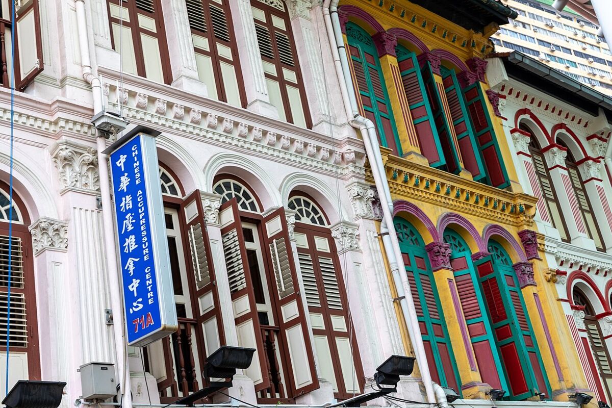 Brightly painted heritage shophouse facades with louvered shutters along Pagoda Street in Chinatown Singapore