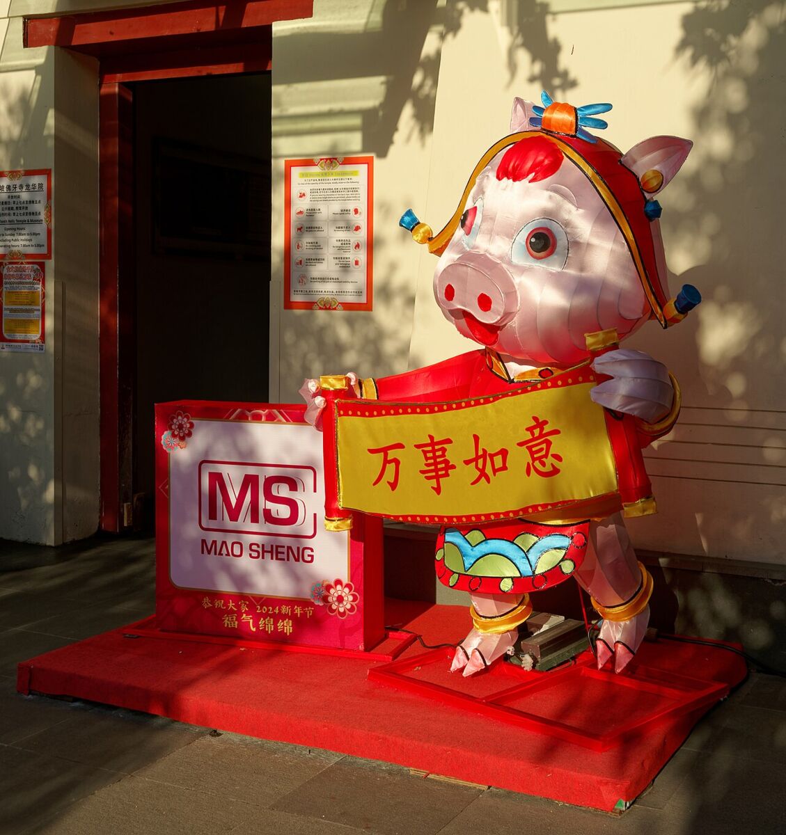 Festive Chinese New Year lantern figure holding a good-luck banner outside a shop in Chinatown Singapore