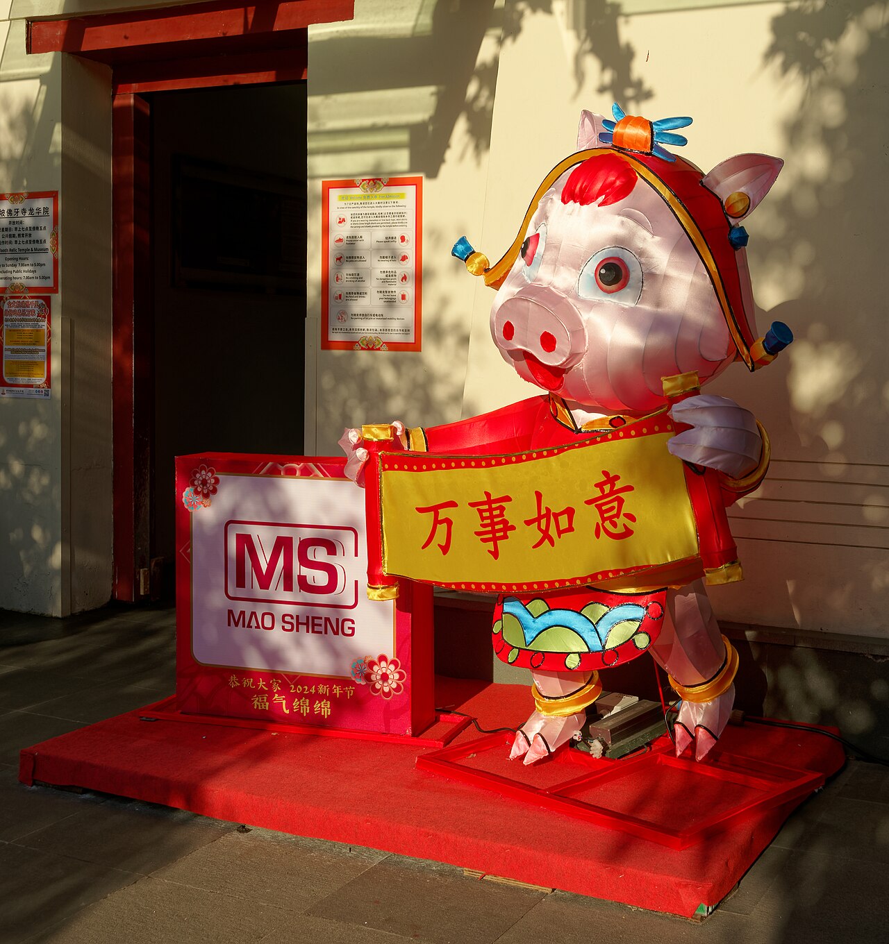 Festive Chinese New Year lantern figure holding a good-luck banner outside a shop in Chinatown Singapore