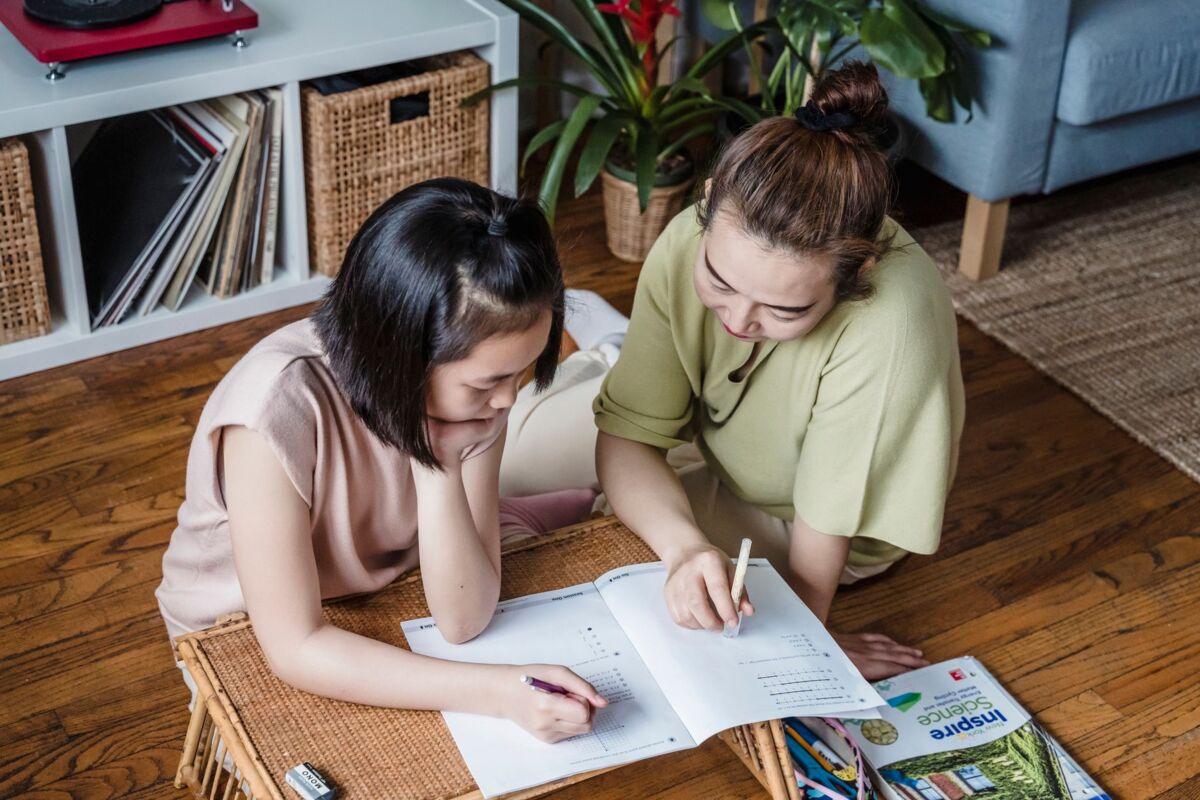 A mother helping her daughter with homework in a cozy home environment, fostering learning.