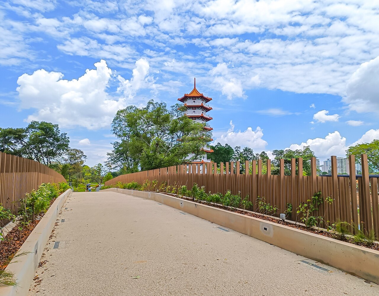 Paved garden pathway leading toward the Chinese Garden pagoda under bright blue skies