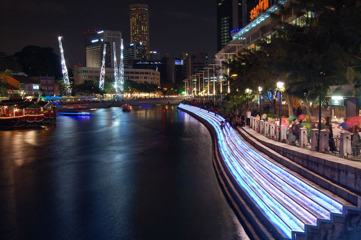 Illuminated blue LED riverside steps and promenade diners along the Singapore River at Clarke Quay at night