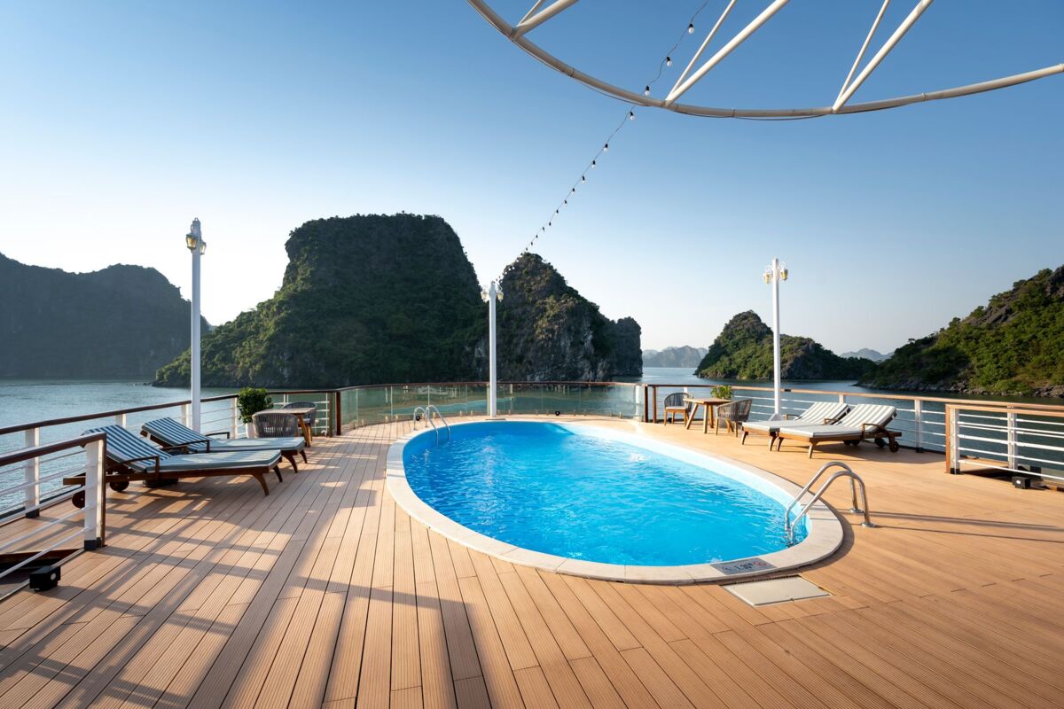 Relaxing cruise ship deck with pool overlooking Ha Long Bay's scenic limestone islands.