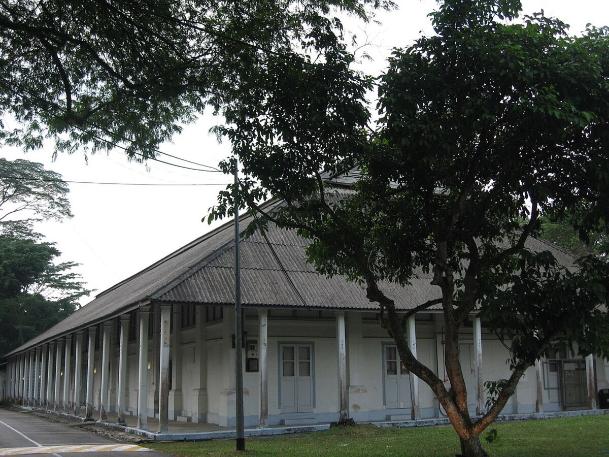 Long colonnaded colonial barrack building framed by mature trees at Tanglin Village, Dempsey Hill
