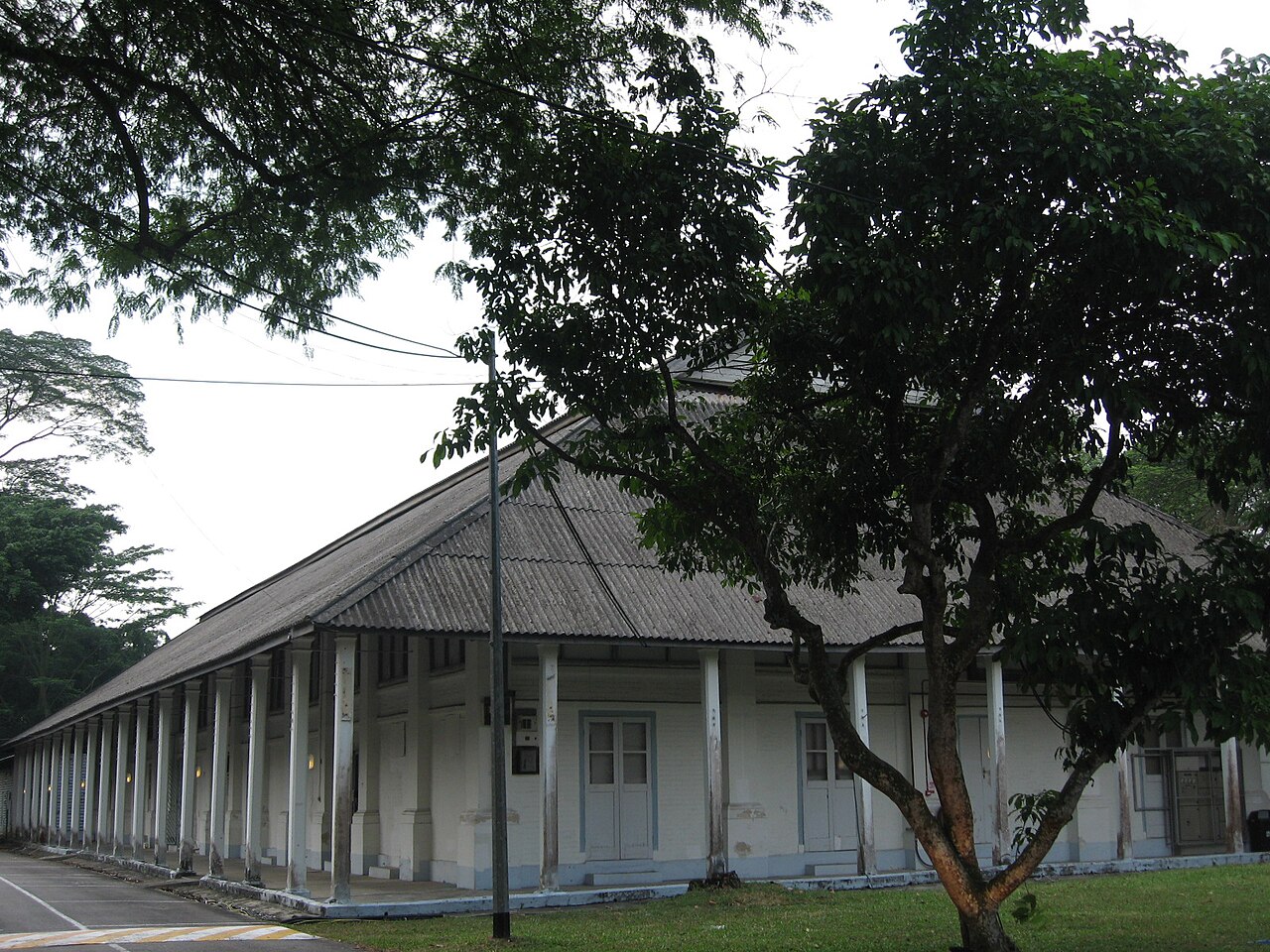 Long colonnaded colonial barrack building framed by mature trees at Tanglin Village, Dempsey Hill
