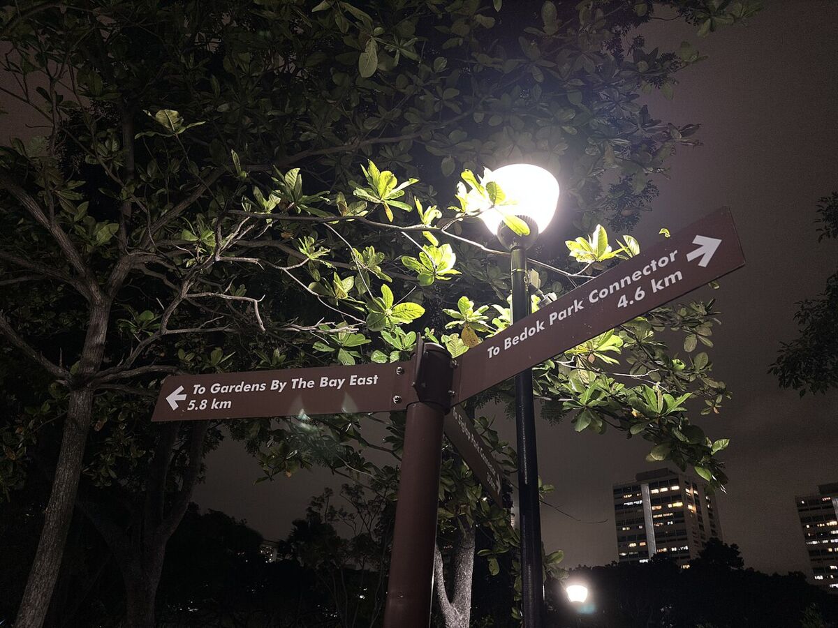 Park connector directional signpost at East Coast Park pointing to Gardens by the Bay East and Bedok Park Connector at night