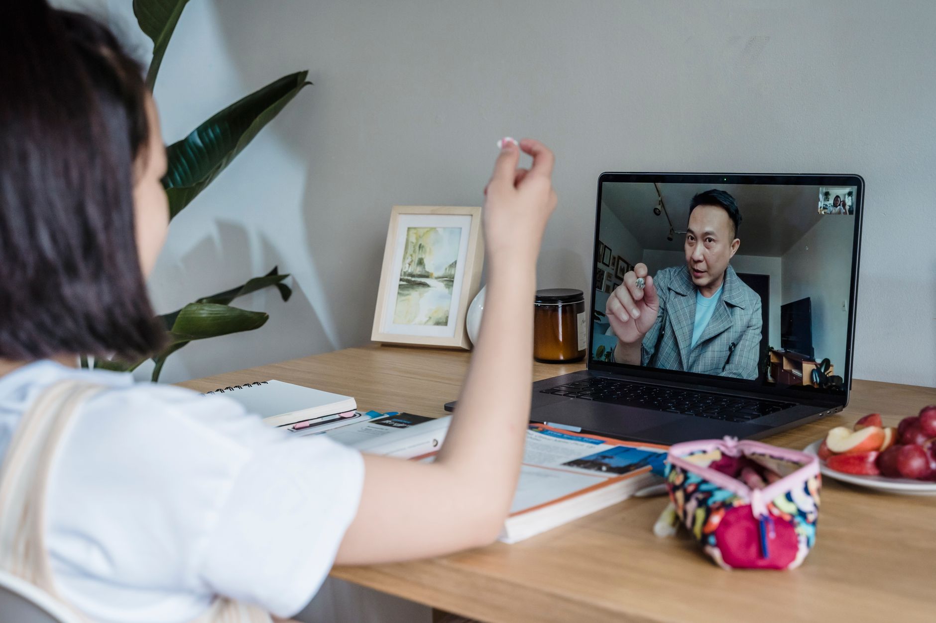 Child attends an online class with a teacher via video call on a laptop.