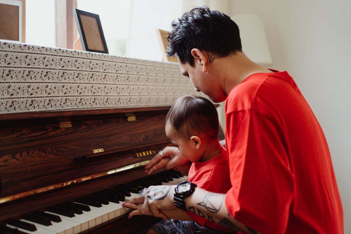 A father and son bonding over a piano lesson indoors, creating cherished musical memories.