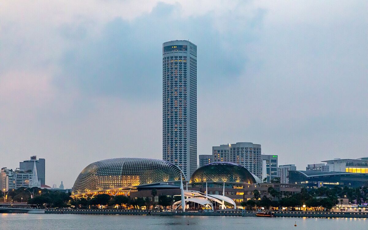 Wide Marina Bay view of the Esplanade twin domes lit at dusk with the tall Swissotel tower rising behind