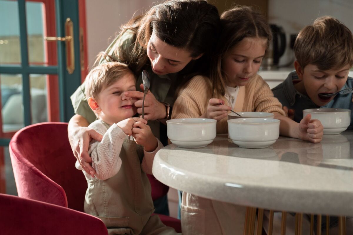 A loving mother with her children enjoying breakfast together in a sunlit kitchen.