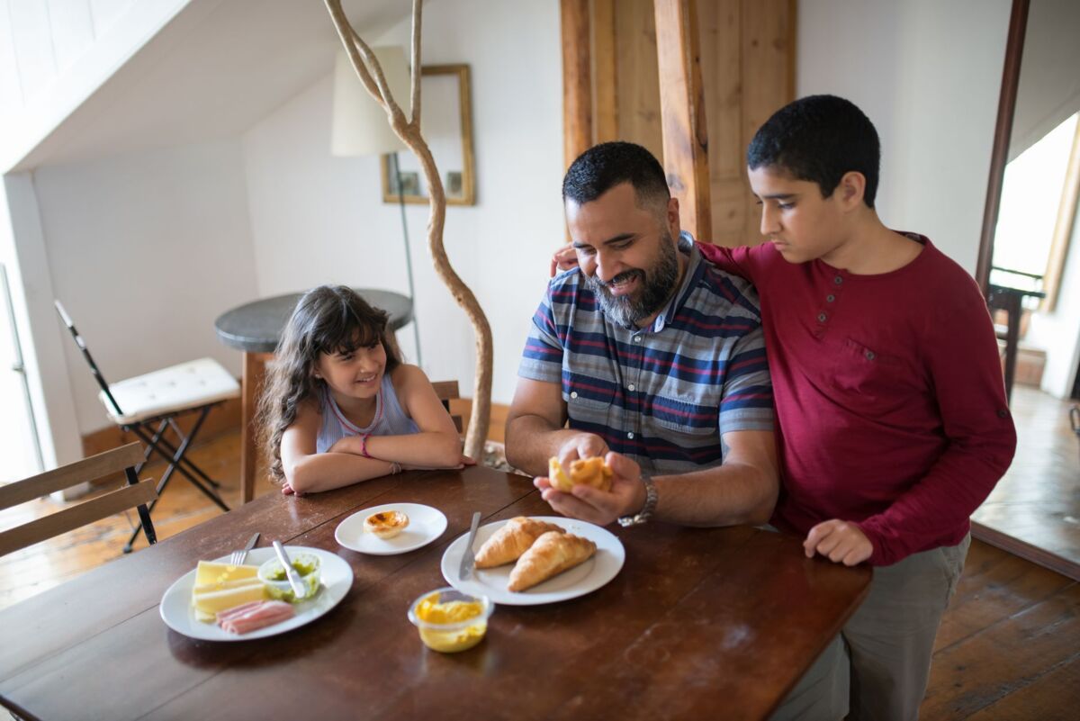 A father and his children enjoying breakfast at home, fostering family bonding.