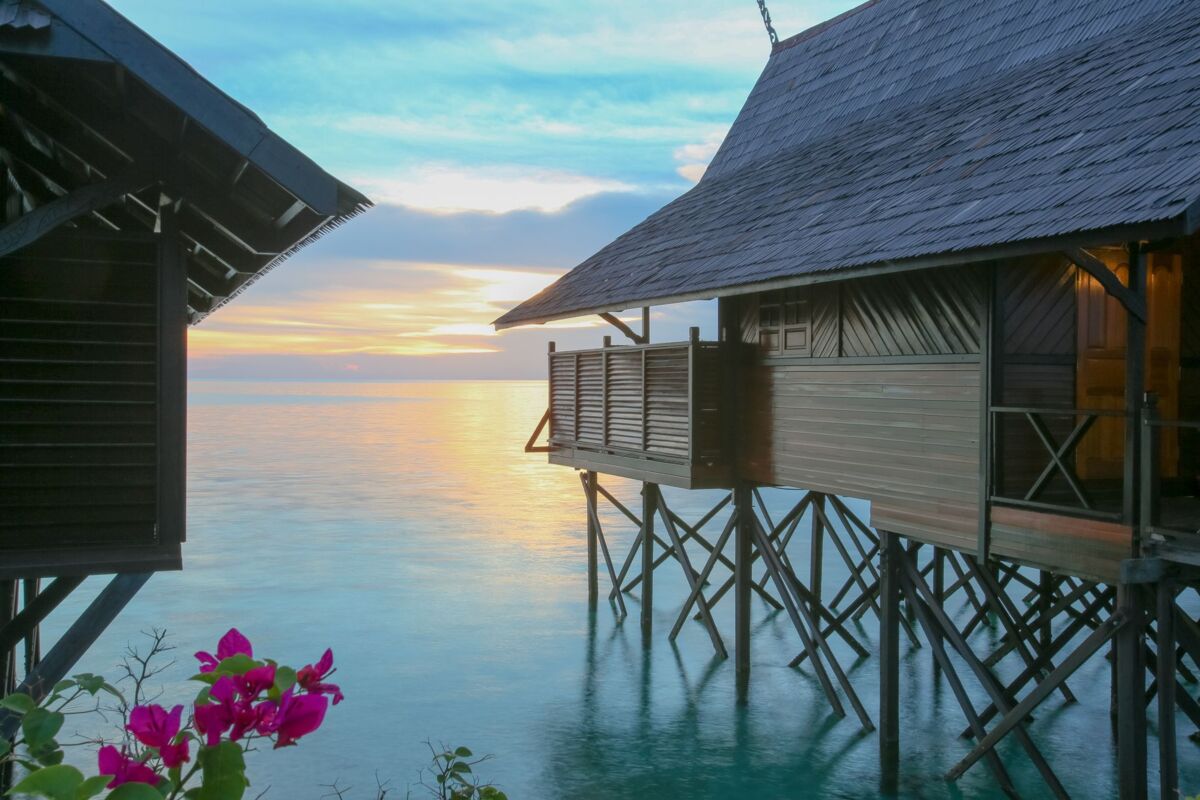 Experience a serene sunrise by overwater bungalows in Malaysia, perfect for a tropical getaway.