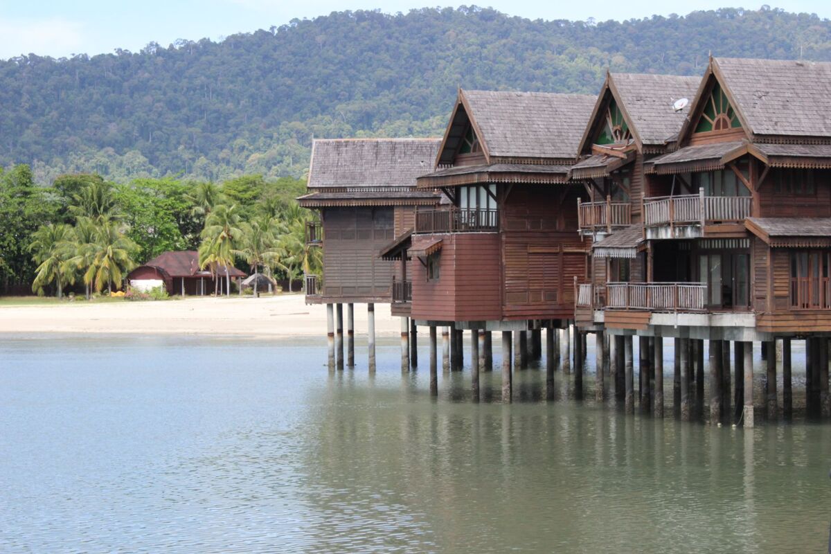 Serene wooden beach houses over water with lush tropical background, ideal for travel and architecture themes.