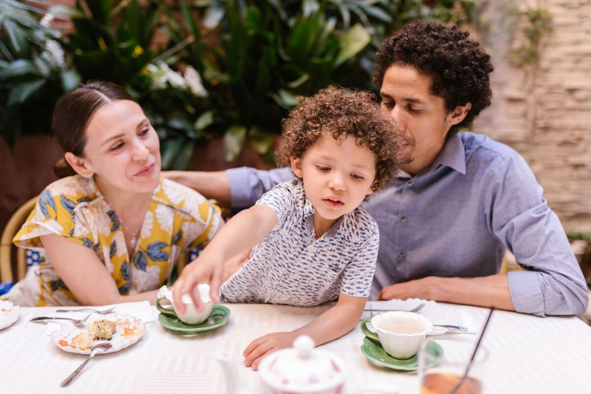 A family of three enjoying dessert and drinks at a cozy indoor cafe setting.