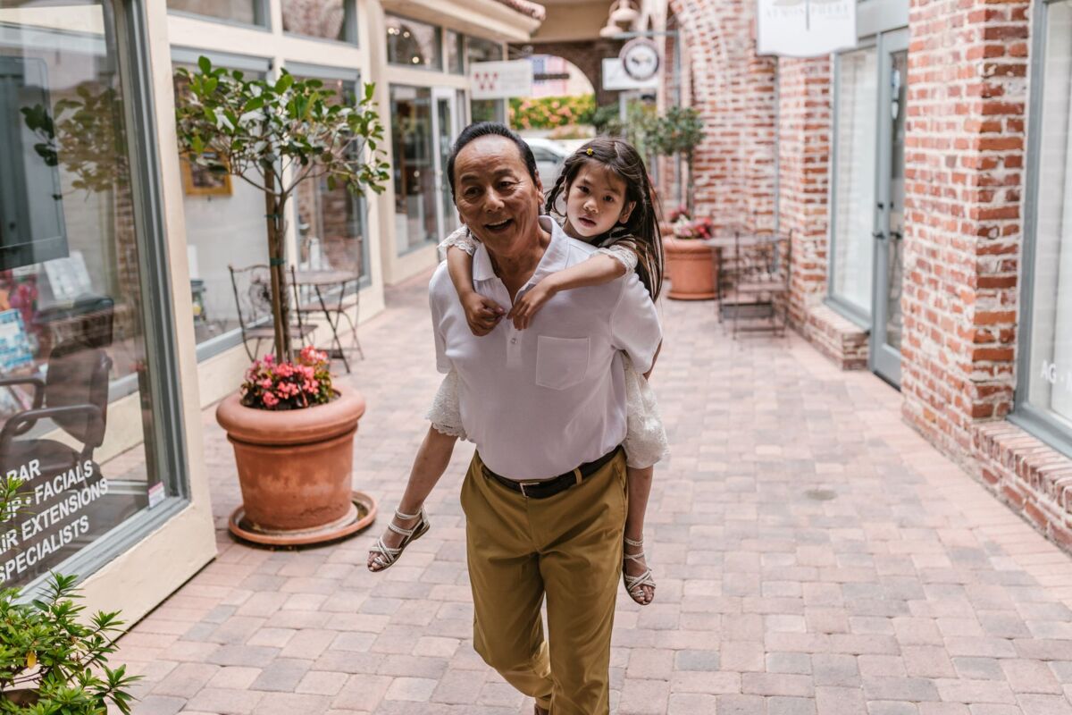 A cheerful moment between grandfather and granddaughter enjoying a piggyback ride in an outdoor mall.