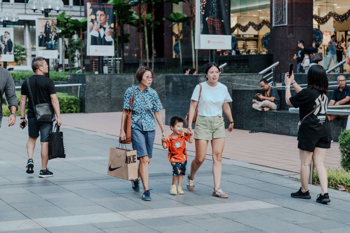 A bustling urban street scene with shoppers and families, capturing vibrant city life.
