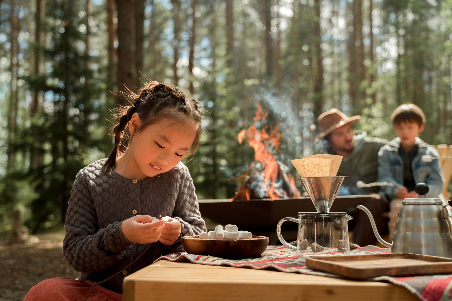 A young girl with marshmallows at a cozy outdoor camping scene by the campfire.
