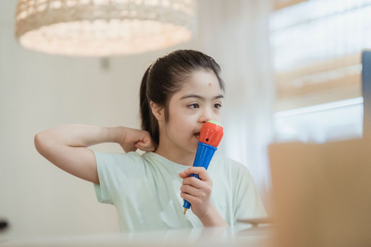 A young girl enthusiastically playing with a colorful toy microphone indoors, expressing joy and creativity.