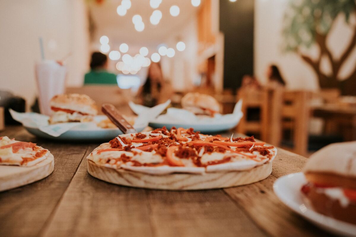Close-up of a freshly baked pizza with toppings on a rustic wooden table at a cozy restaurant.