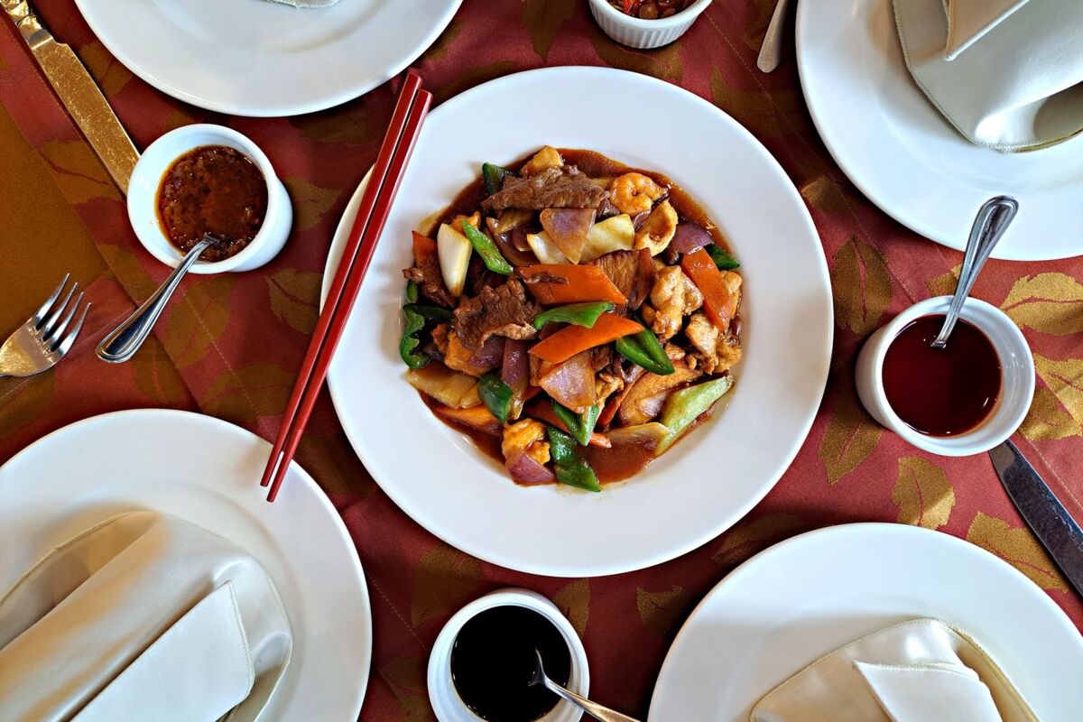 Colorful Chinese stir fry dish with vegetables, served on elegant table setting with chopsticks.