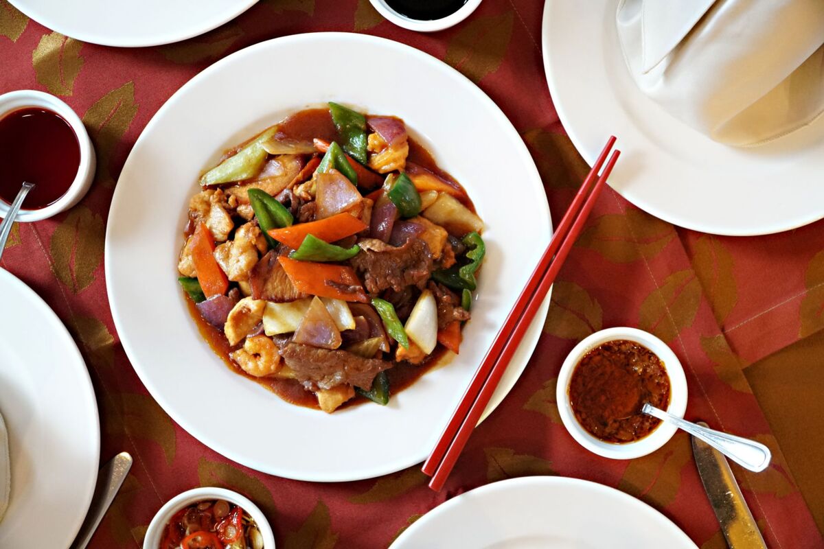 A vibrant Chinese stir-fry dish featuring beef, vegetables, and sauces, beautifully presented with chopsticks.