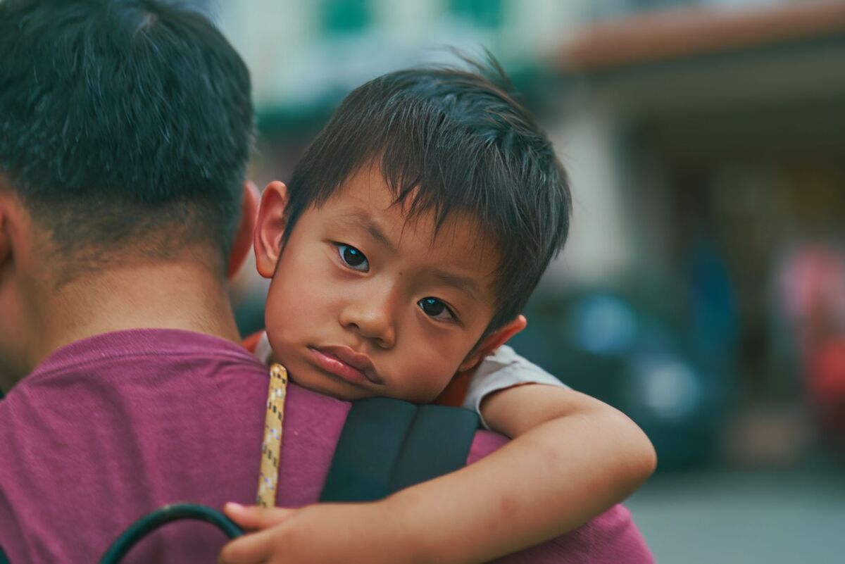 A heartwarming scene of a father carrying his son outdoors in Singapore.