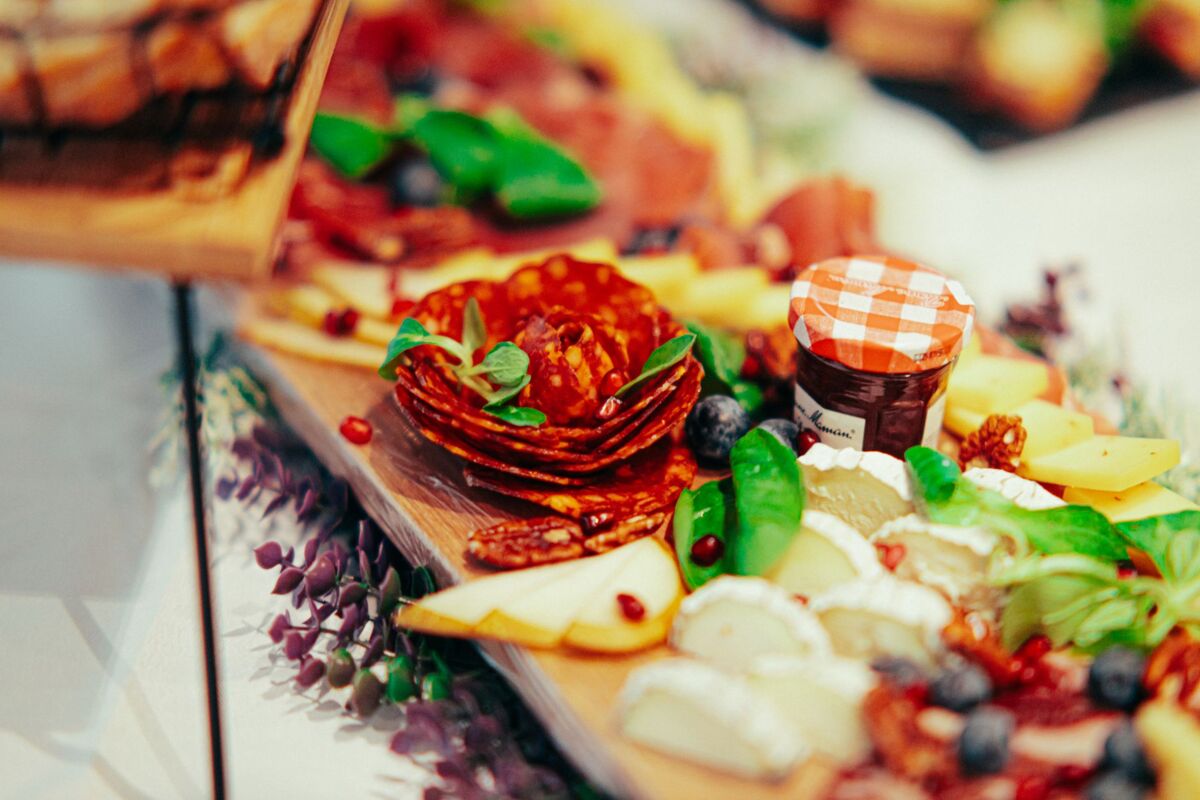 Colorful charcuterie board featuring meats, cheeses, and fresh herbs.